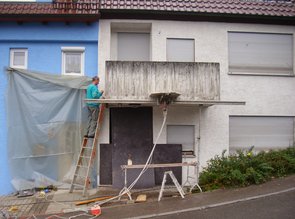 Eine Stahlbetonbrüstung wird abgesägt. Hier sieht man die Vorbereitungen: die Hauswand wird durch Folie gegen das Spritzwasser der Säge geschützt. Die Tür und das Fenster im EG werden abgedeckt.